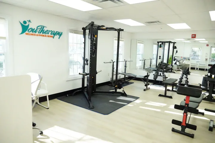 The open gym floor at Youtherapy Wellness and Physical Rehab in Milford, under the Youtherapy logo painted on the wall
