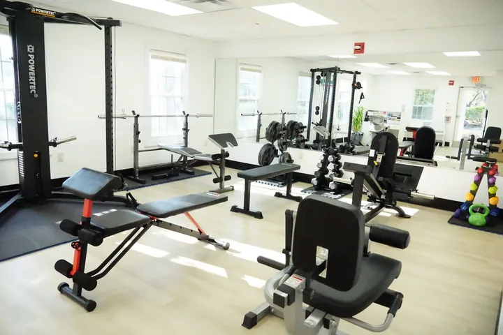 Weight racks and benches on the training floor at Youtherapy Wellness and Physical Rehab in Milford