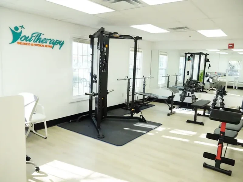 The open gym floor at Youtherapy Wellness and Physical Rehab in Milford, under the Youtherapy logo painted on the wall