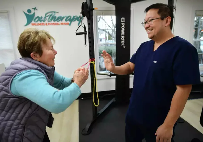 Physical therapist guiding an older adult through a hands-on treatment session